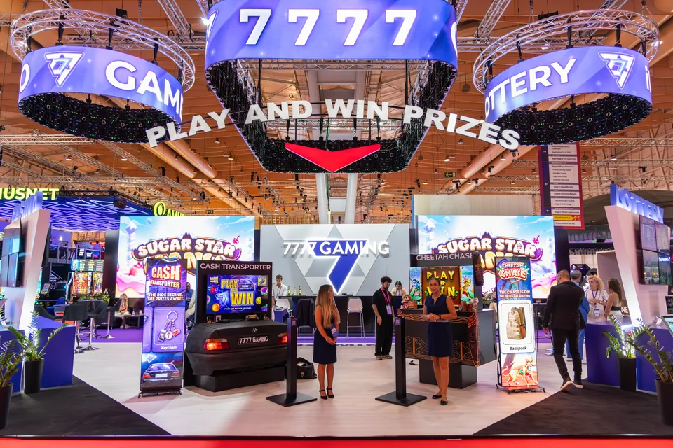 Suspended LED rings and display totems at the 7777 Gaming stand at SBC Summit Lisbon 2025